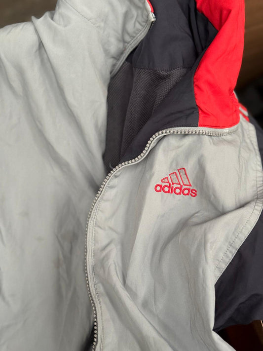 Close-up of a gray jacket with an Adidas logo on a wooden surface