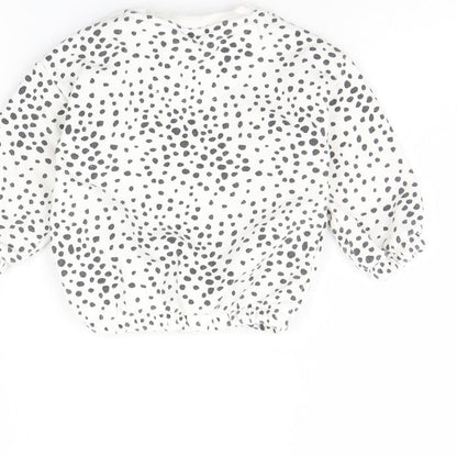 Brand and care label for F&F girls’ white polka dot jumper, size 6-9, months