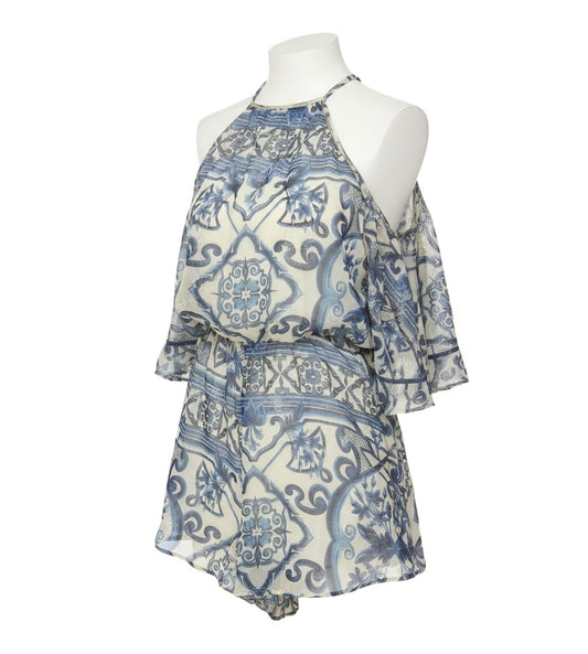 Prewornwholesale blue and ivory metallic baroque print playsuit with a cape overlay and high neckline on a mannequin.